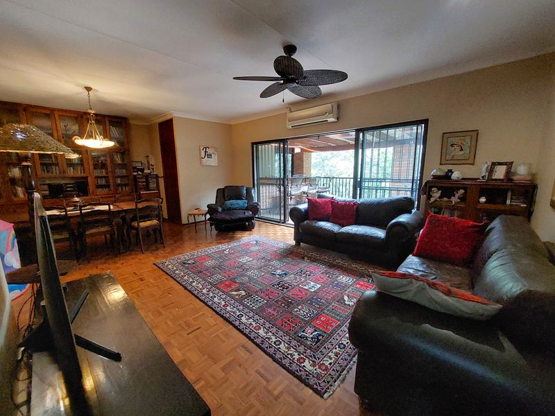 Spacious open-plan living and dining area featuring parquet flooring, built-in cabinetry, and sliding glass doors leading to an outdoor patio.
