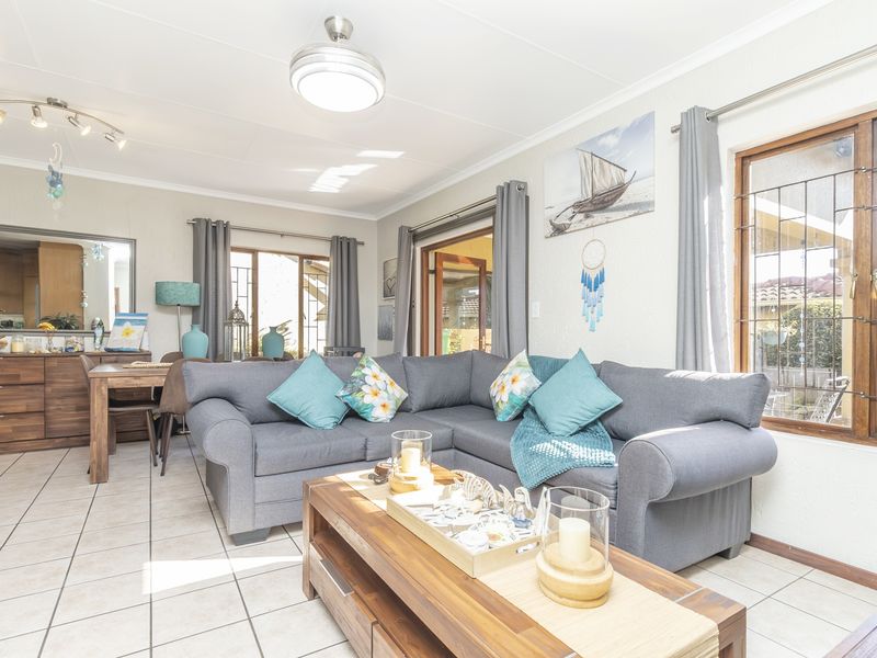Open-plan living and dining area featuring tiled flooring, ceiling fan, and direct access to the outdoor space through sliding glass doors.