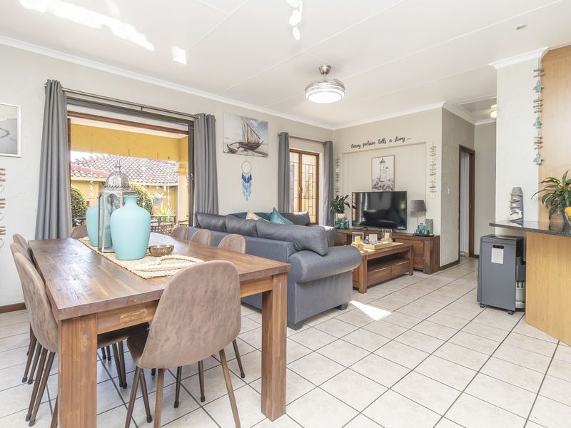 Spacious open-plan living and dining area featuring tiled flooring, a ceiling fan, and direct access to an outdoor patio through sliding glass doors.