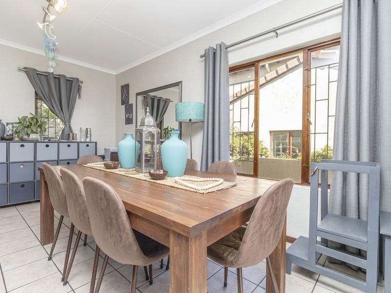 A dining room featuring tiled flooring, timber-framed windows with security bars, and decorative cove cornicing.