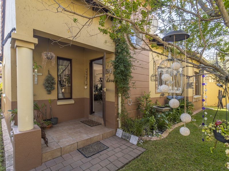 A welcoming front entrance featuring a tiled porch, concrete column, and a well-maintained garden area leading to the main doorway.