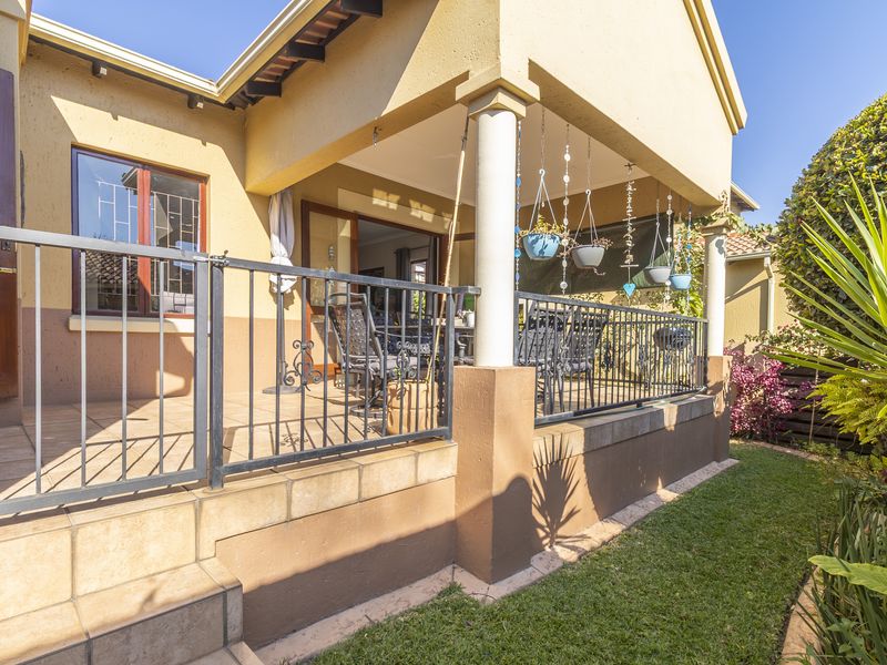A covered outdoor patio area featuring tiled flooring, metal balustrades, and concrete columns, providing direct access to the interior living space.