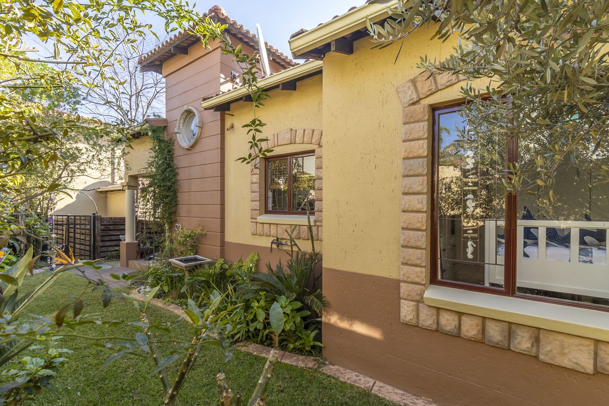 A view of the rear exterior facade featuring textured walls, stone window detailing, and a well-maintained garden area.
