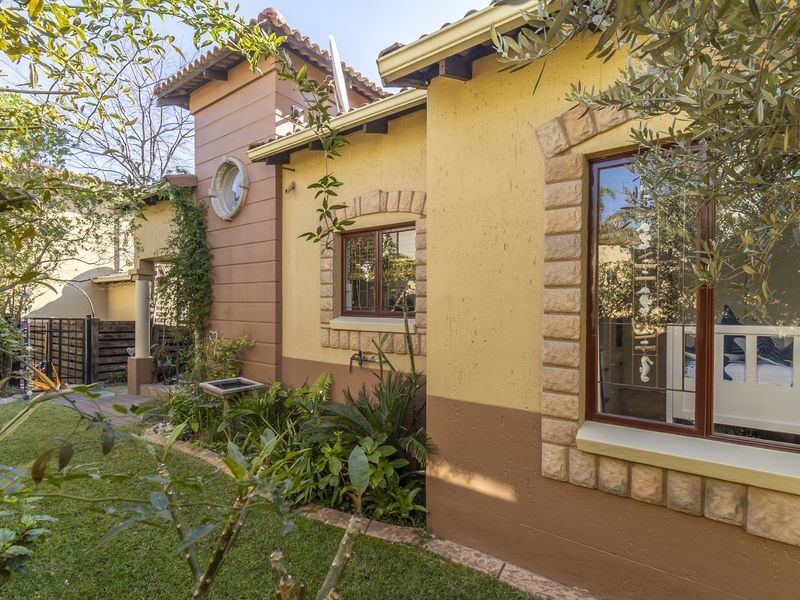A view of the rear exterior facade featuring textured walls, stone window detailing, and a well-maintained garden area.