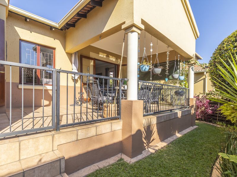 A covered outdoor patio area featuring tiled flooring, concrete support columns, and a metal balustrade, providing a functional space for outdoor relaxation.
