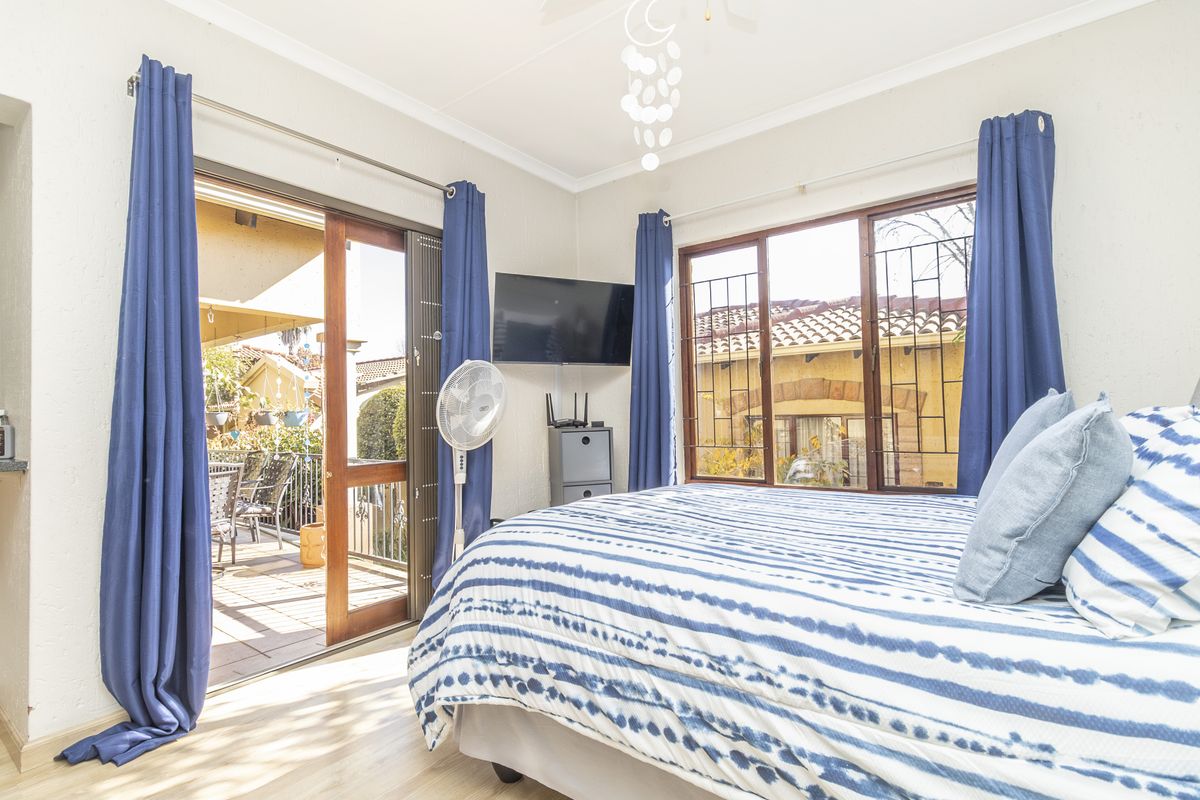 A bright bedroom featuring laminate flooring, a ceiling fan, and direct access to an outdoor patio through a sliding glass door.