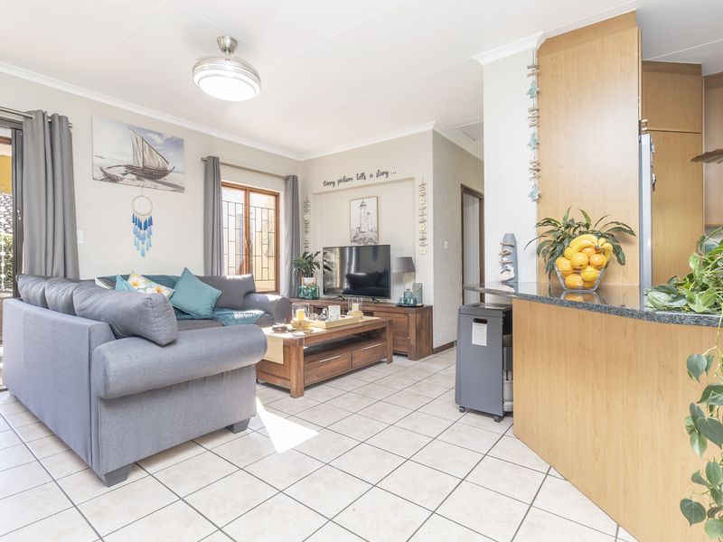 Open-plan living area featuring tiled flooring, a granite kitchen breakfast bar, and direct access to an outdoor patio through sliding glass doors.