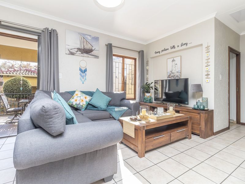 A bright and well-maintained living room featuring tiled flooring and a sliding glass door providing access to an outdoor patio area.