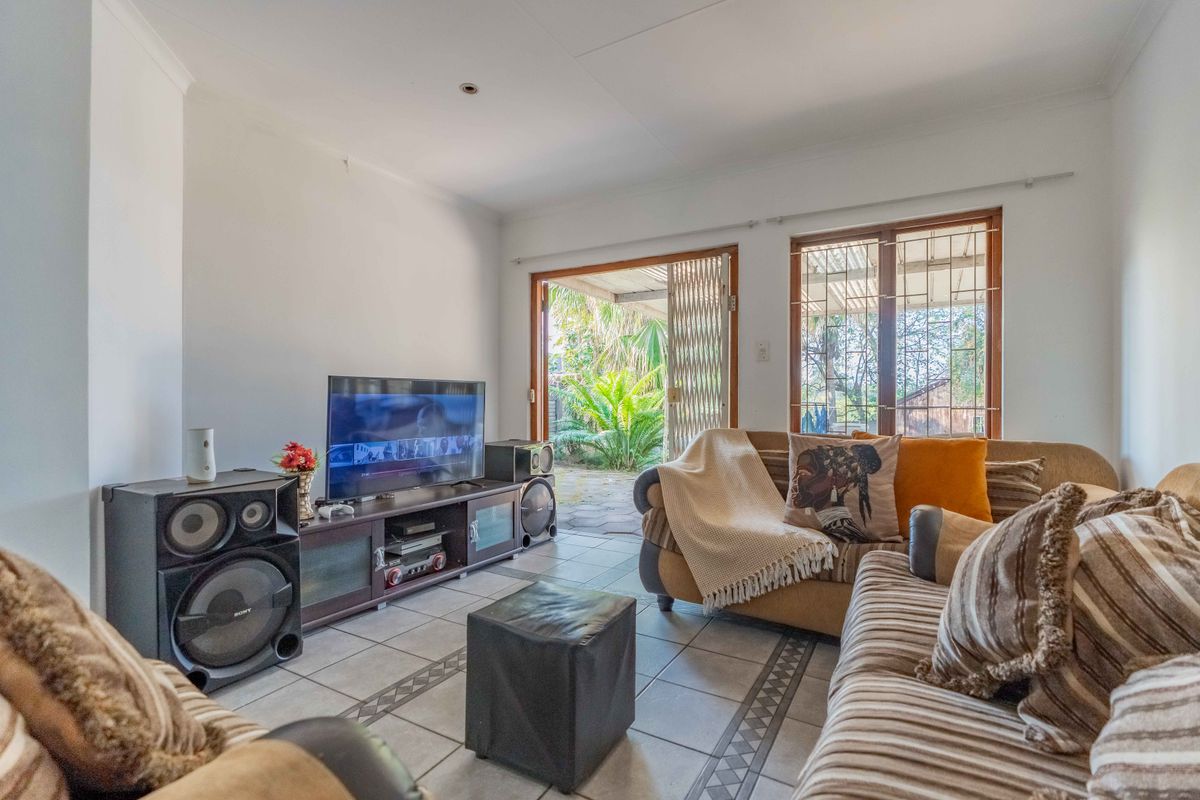 A bright living room featuring tiled flooring and direct access to an outdoor patio area through a sliding glass door.