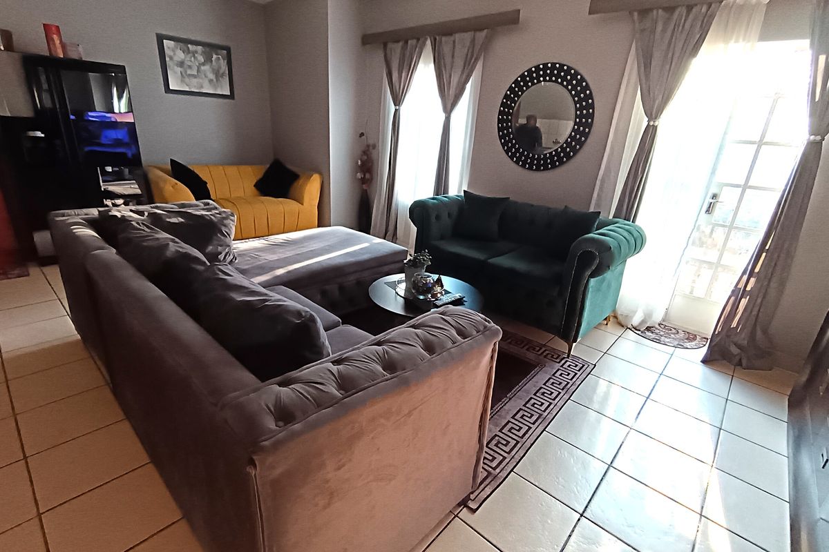 A living room featuring tiled flooring and access to an outdoor area through glass-paned french doors.