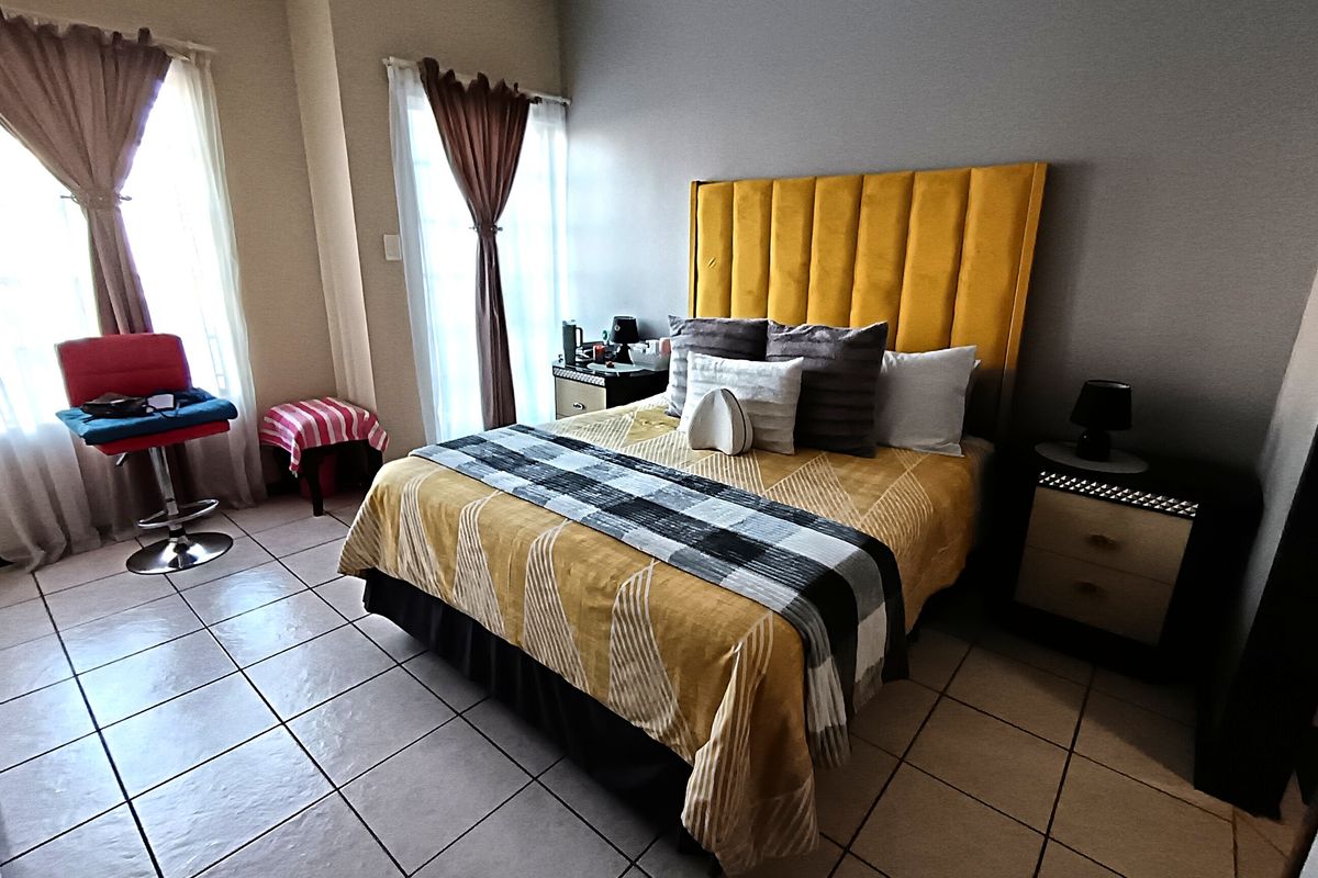 A bedroom featuring tiled flooring and large windows that provide natural light.