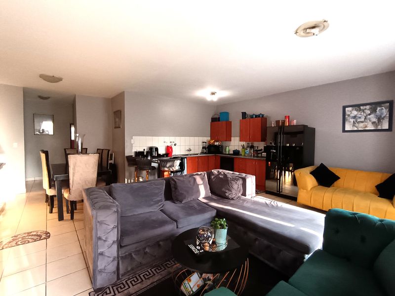 Open-plan living and dining area featuring a functional kitchen with built-in cabinetry and tiled flooring, creating a versatile space for daily living.