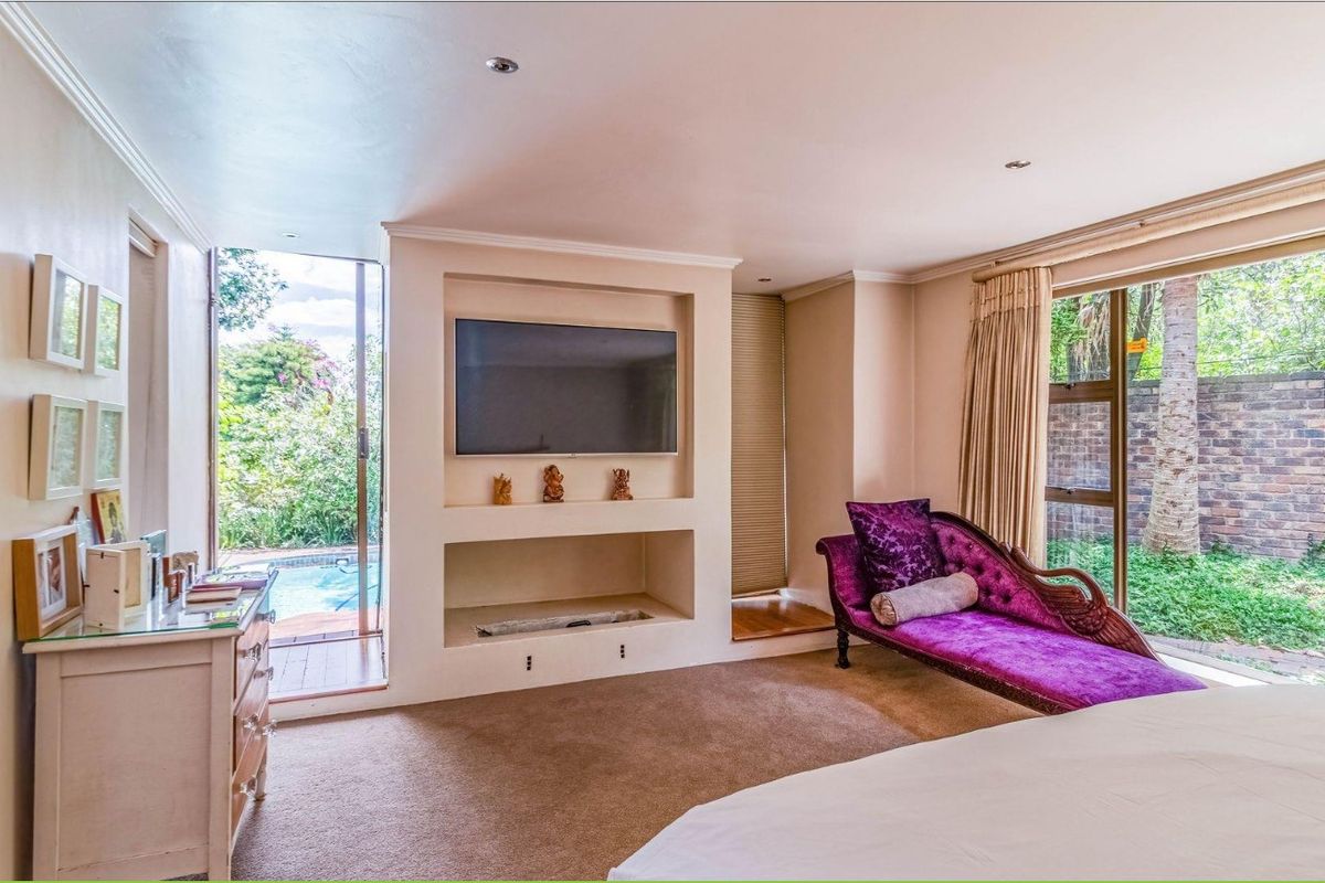 Spacious bedroom featuring a built-in media niche, recessed lighting, and large sliding glass doors providing direct access to the outdoor pool area.