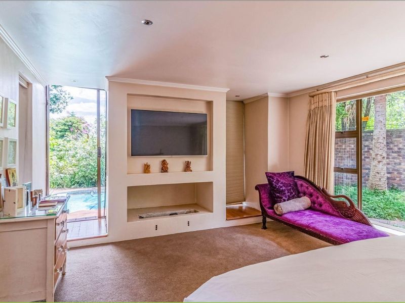 Spacious bedroom featuring a built-in media niche, recessed lighting, and large sliding glass doors providing direct access to the outdoor pool area.