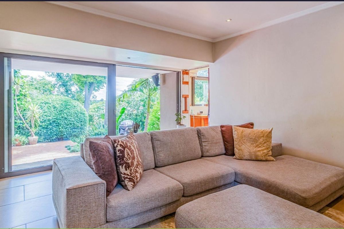 A comfortable living room featuring large sliding glass doors that provide seamless access to the garden and patio area.