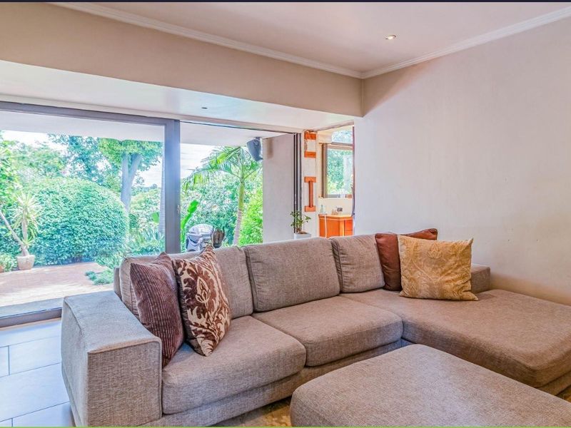 A comfortable living room featuring large sliding glass doors that provide seamless access to the garden and patio area.
