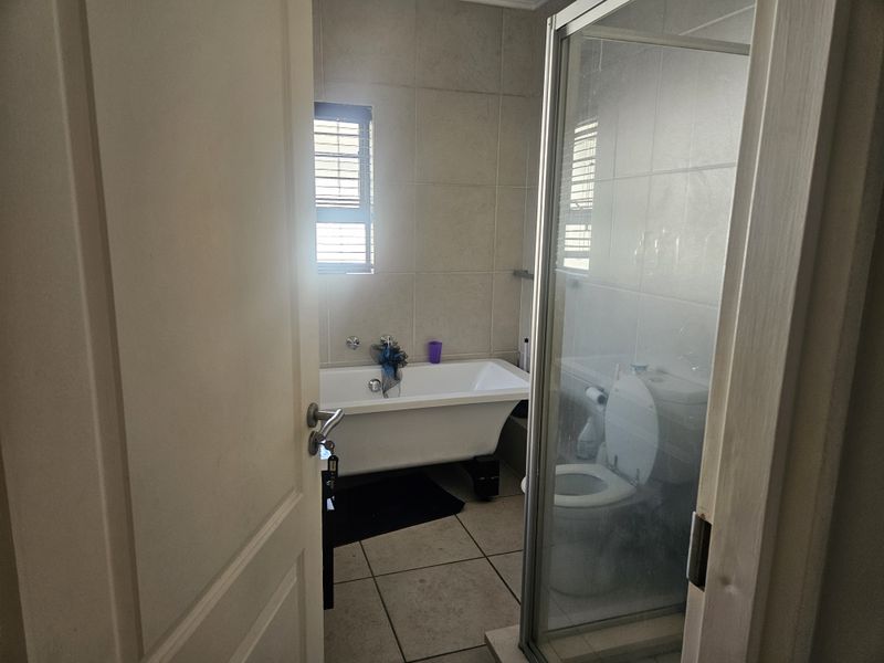 A functional bathroom featuring a freestanding bathtub, a separate glass-enclosed shower, and tiled finishes throughout.