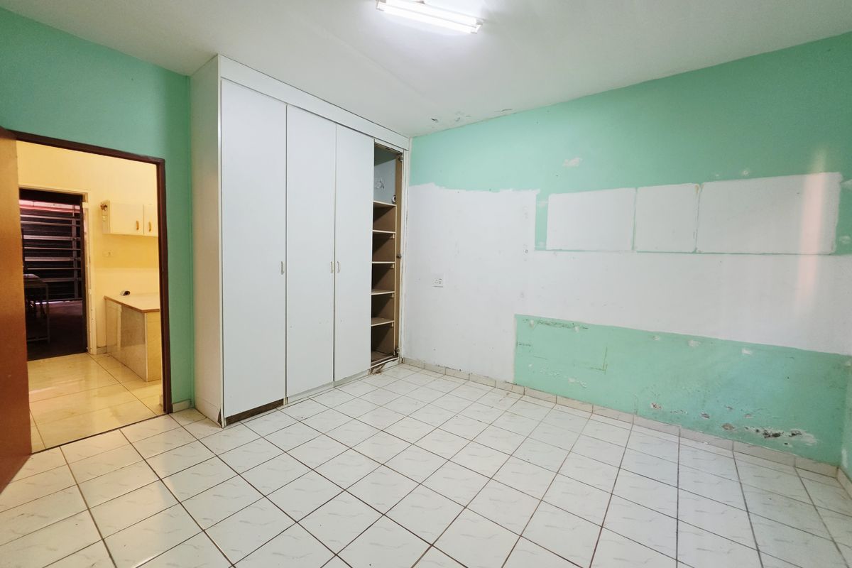 An empty bedroom featuring tiled flooring, a built-in wardrobe, and walls requiring cosmetic repair and repainting.