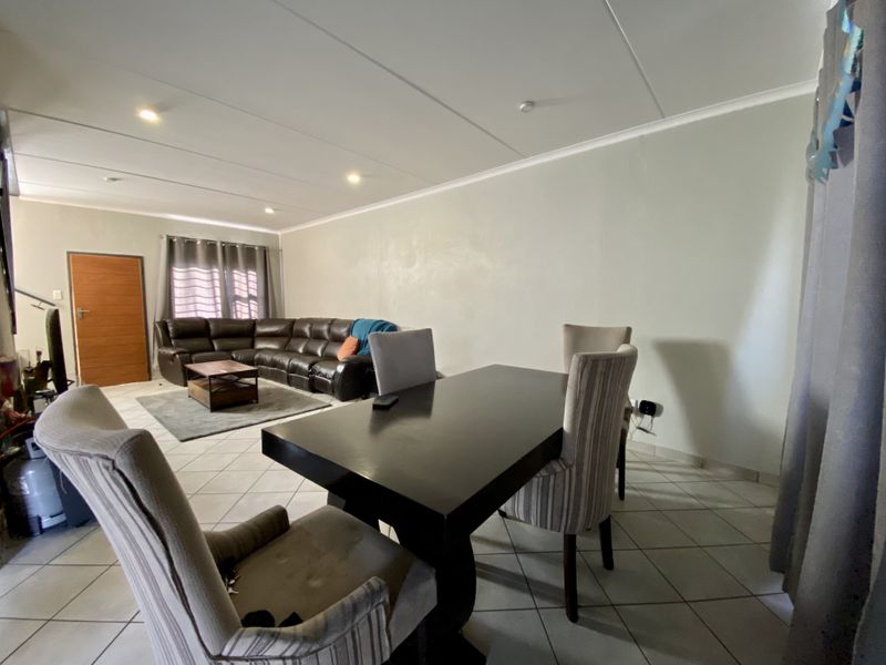 An open-plan living and dining area featuring tiled flooring, recessed downlighting, and a neutral color palette, providing a versatile space for family living.