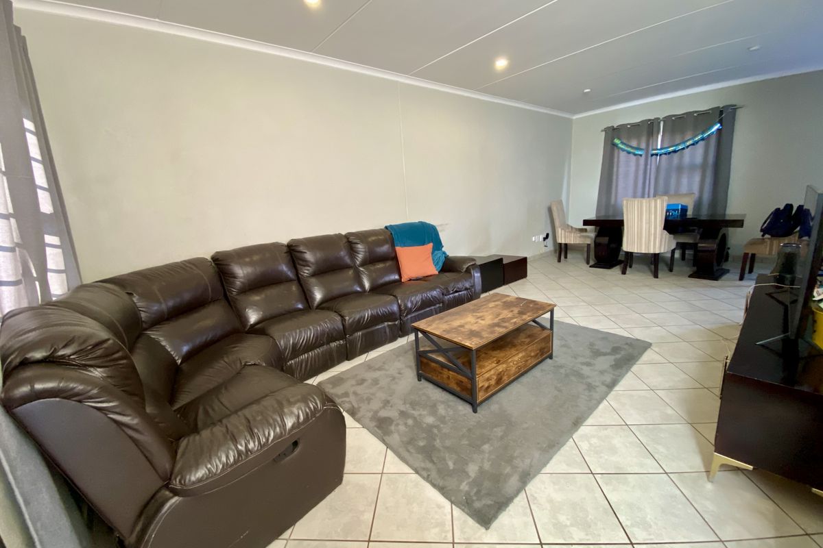 Spacious open-plan living and dining area featuring neutral wall tones, ceramic tiled flooring, and recessed ceiling lighting.