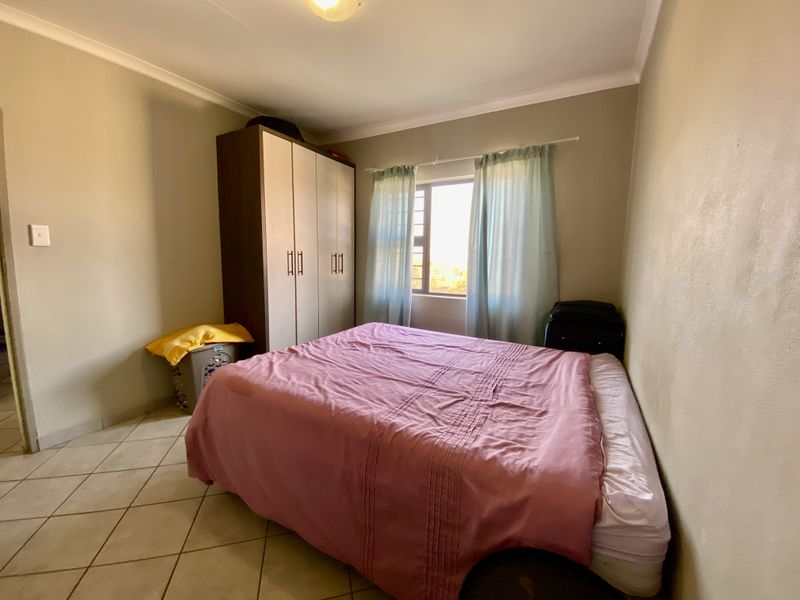 A functional bedroom featuring tiled flooring, a built-in wardrobe, and coved ceiling details, offering a neutral base for personalization.