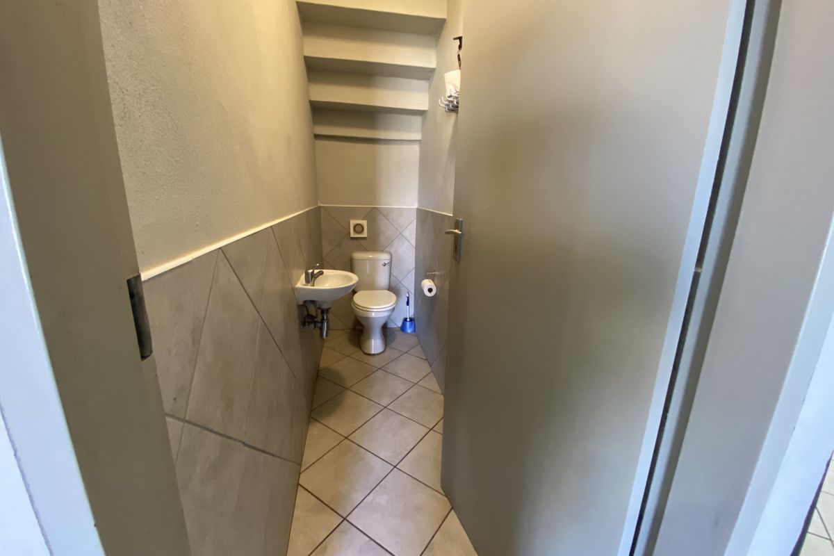 A compact guest bathroom featuring a wall-mounted basin, toilet, and neutral ceramic tiling throughout.