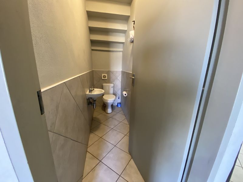 A compact guest bathroom featuring a wall-mounted basin, toilet, and neutral ceramic tiling throughout.