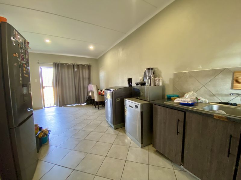 Open-plan living and kitchen area featuring tiled flooring, neutral walls, and direct access to an outdoor space through a sliding door.