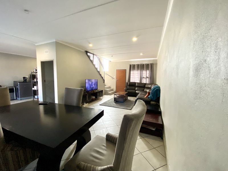 Open-plan living and dining area featuring tiled flooring, a staircase, and neutral wall finishes, providing a functional layout for daily living.