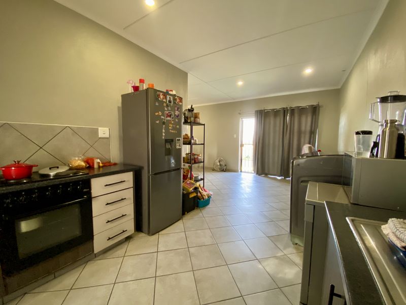 Open-plan kitchen and living area featuring tiled flooring, built-in oven, hob, and direct access to the exterior via a sliding door.