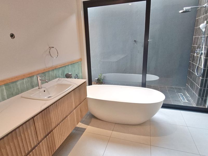 Modern bathroom featuring a freestanding bathtub, double vanity, and a walk-in shower with floor-to-ceiling glass overlooking a private outdoor area.