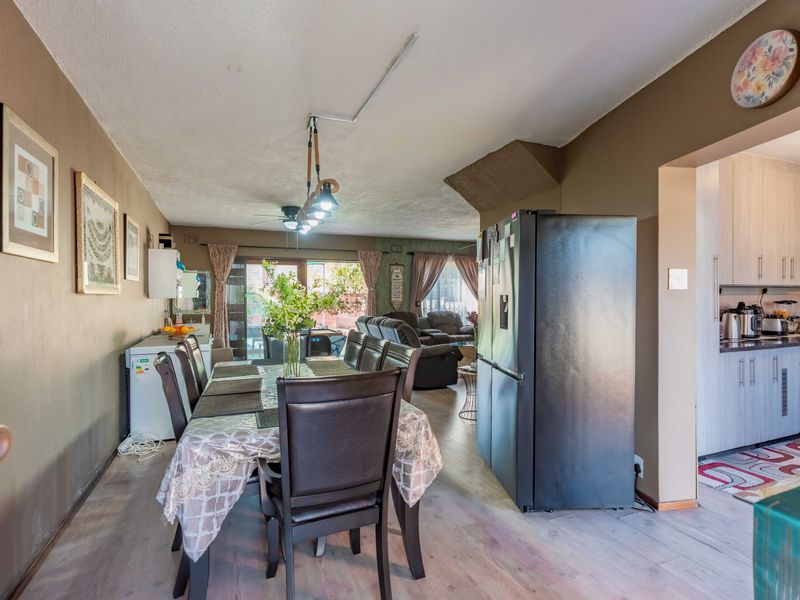 Open-plan living and dining area featuring laminate flooring, ceiling fan, and direct access to the patio, adjacent to a functional kitchen space.