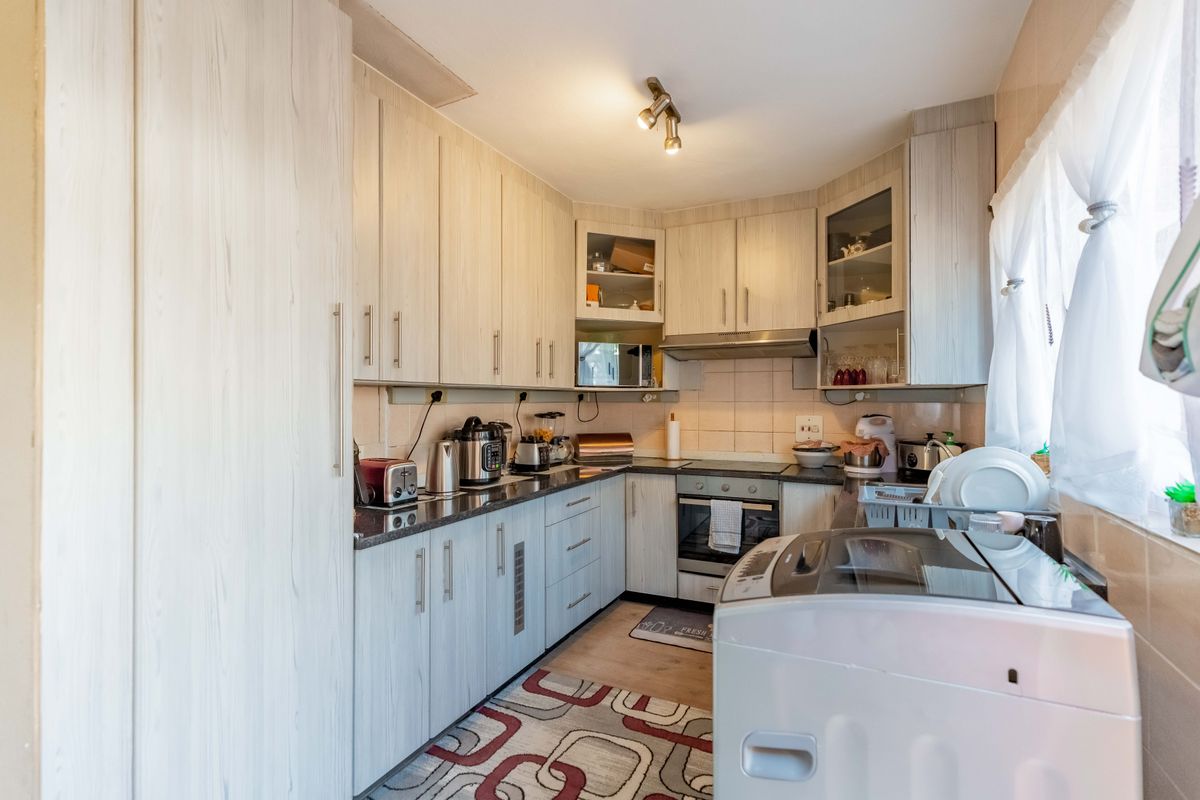 A functional kitchen featuring light wood-grain cabinetry, granite countertops, a built-in oven, and an extractor fan, providing ample storage and workspace.