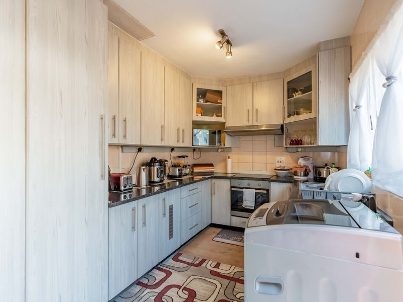 A functional kitchen featuring light wood-grain cabinetry, granite countertops, a built-in oven, and an extractor fan, providing ample storage and workspace.