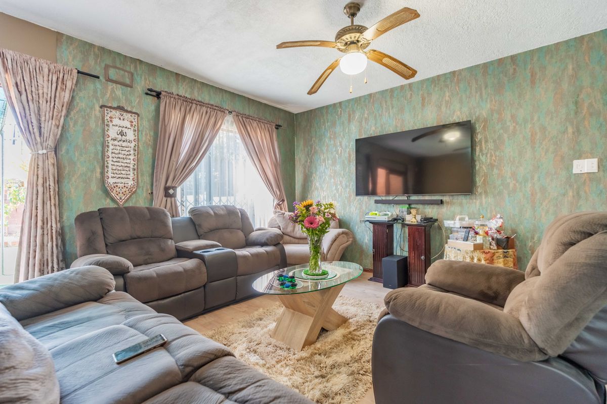 A living room featuring laminate flooring, a ceiling fan, and textured walls, providing a comfortable and functional space for relaxation.