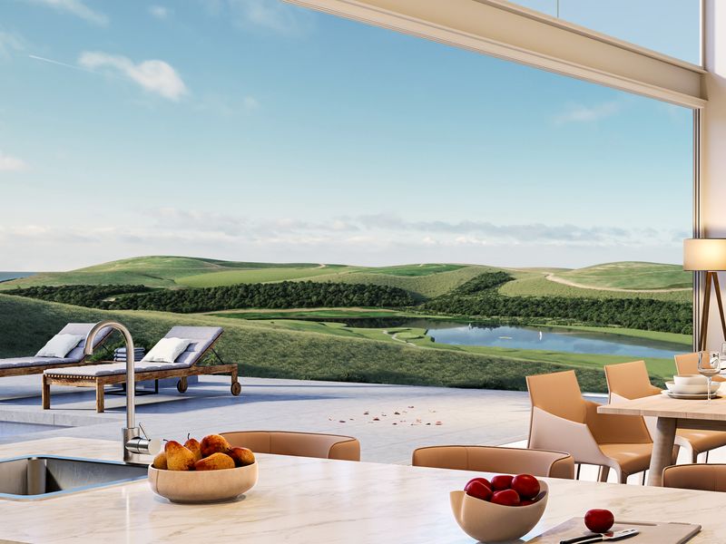 Modern open-plan living area featuring a sleek kitchen island with marble countertop, flowing seamlessly onto a patio with pool and expansive landscape views.