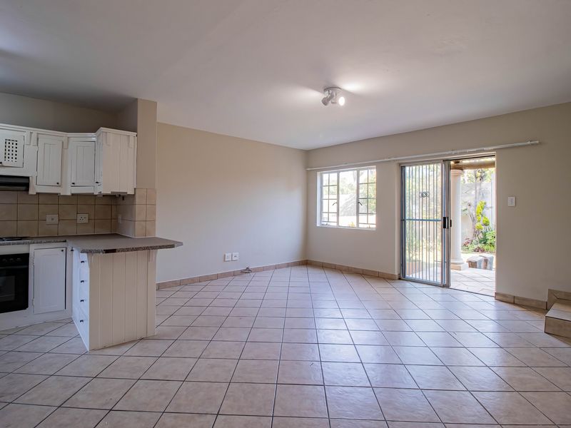 Spacious open-plan living area featuring a functional kitchen with built-in appliances, tiled flooring throughout, and direct access to an outdoor patio area.