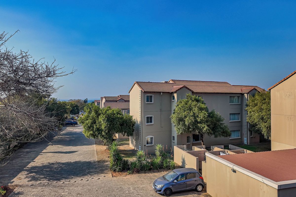 Aerial view of a townhouse complex featuring multi-story residential units, paved driveways, and established landscaping.