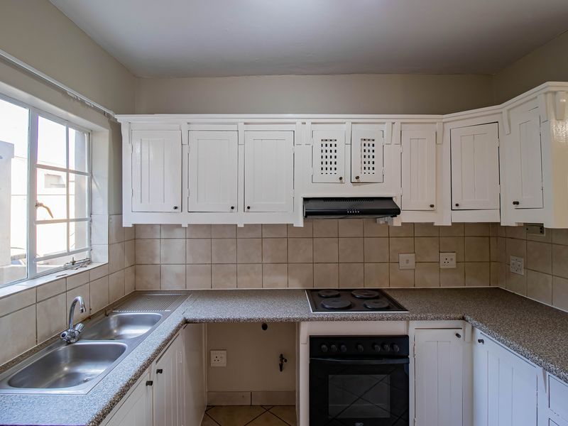 A functional kitchen featuring white cabinetry, granite countertops, a double basin sink, and built-in oven with extractor fan.