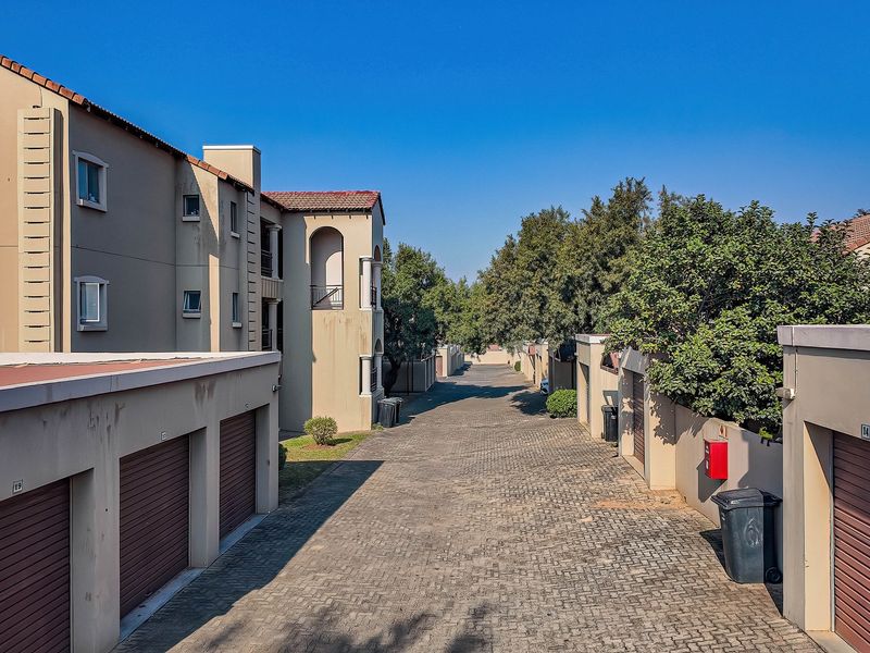 A view of the townhouse complex driveway featuring multiple garage units and multi-story residential buildings with paved access.