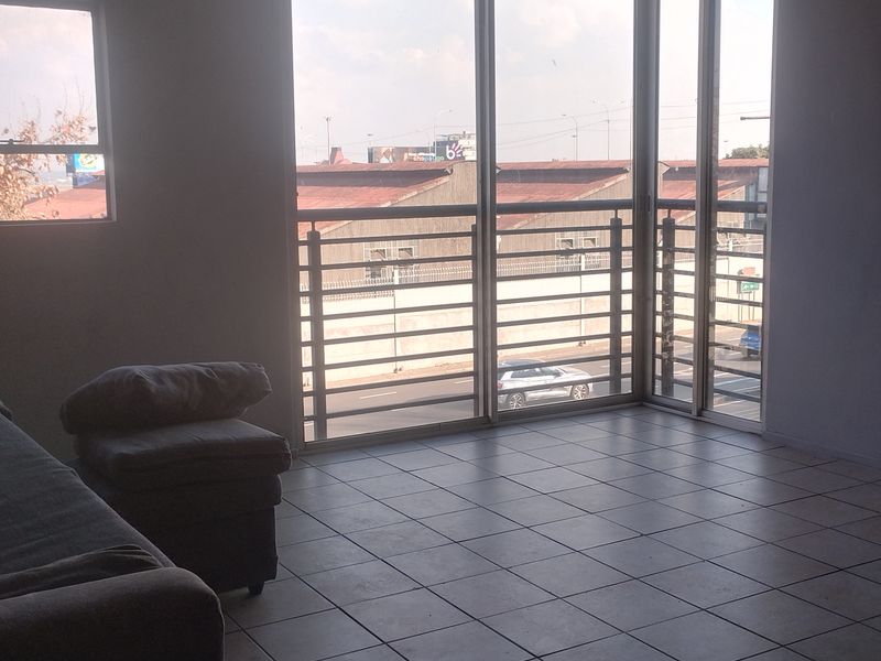 An empty living area featuring tiled flooring and large glass sliding doors that open to a balcony with an urban view.