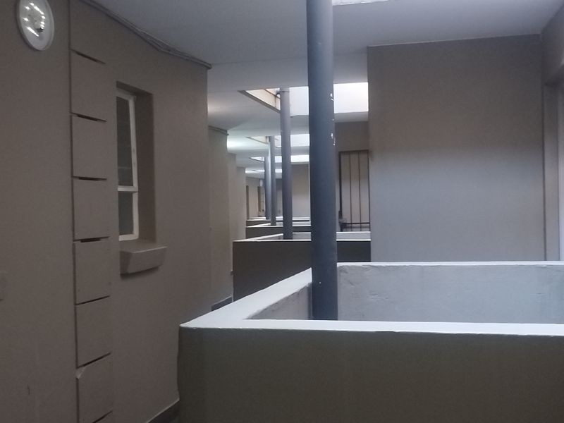An exterior apartment building corridor featuring structural columns and parapet walls with visible signs of wear on the wall finishes.