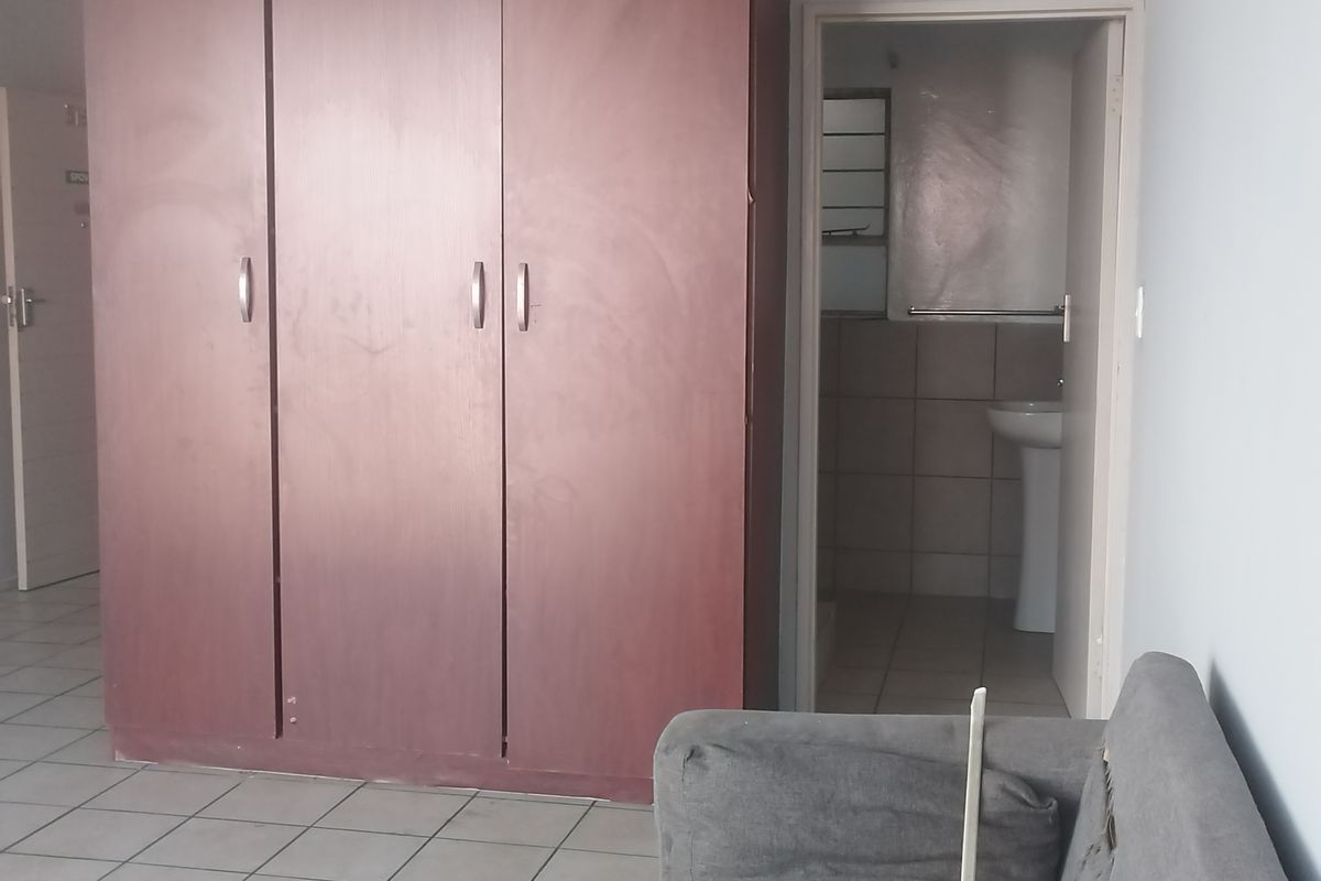 Bedroom featuring a large built-in wardrobe, tiled flooring, and an adjoining en-suite bathroom with a pedestal basin.
