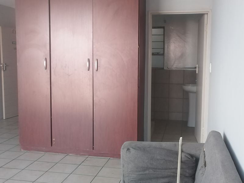 Bedroom featuring a large built-in wardrobe, tiled flooring, and an adjoining en-suite bathroom with a pedestal basin.