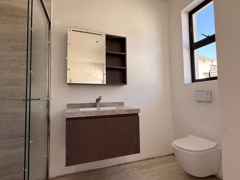 Modern bathroom featuring a wall-mounted vanity, glass shower enclosure, and wall-hung toilet. The space requires minor finishing touches to complete the installation.
