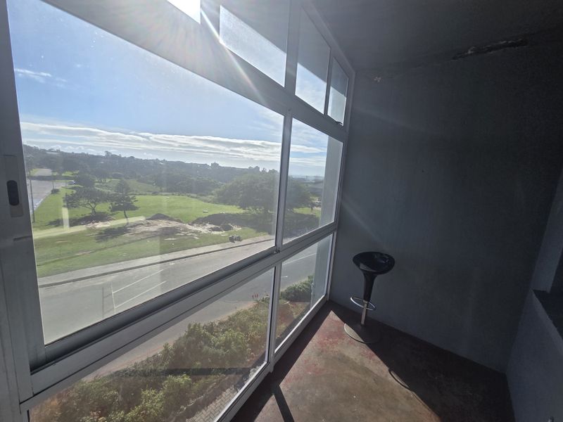 Enclosed balcony area featuring large glass windows with expansive outdoor views and concrete flooring, offering potential for a bright, modern sunroom or lounge space.