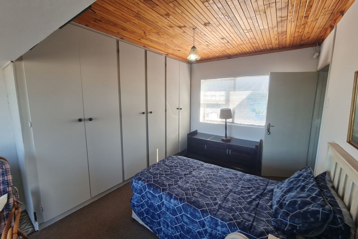 A bedroom featuring extensive built-in cupboards and a distinctive timber tongue and groove ceiling, offering functional storage space.