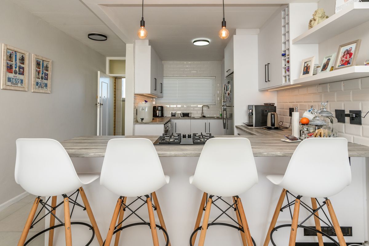 Modern kitchen featuring white cabinetry, subway tile backsplash, a central breakfast bar with an integrated gas hob, and stylish pendant lighting.