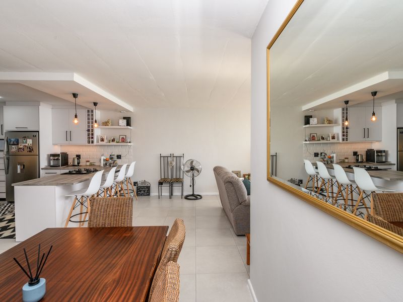 Modern open-plan living area featuring a well-appointed kitchen with stone countertops, subway tile backsplash, and integrated cabinetry, flowing into a spacious dining and lounge area.