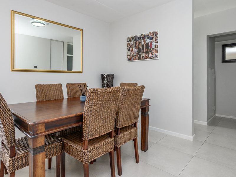 A bright and well-maintained dining area featuring neutral tiled flooring and clean, minimalist wall finishes, providing a versatile space for meals.